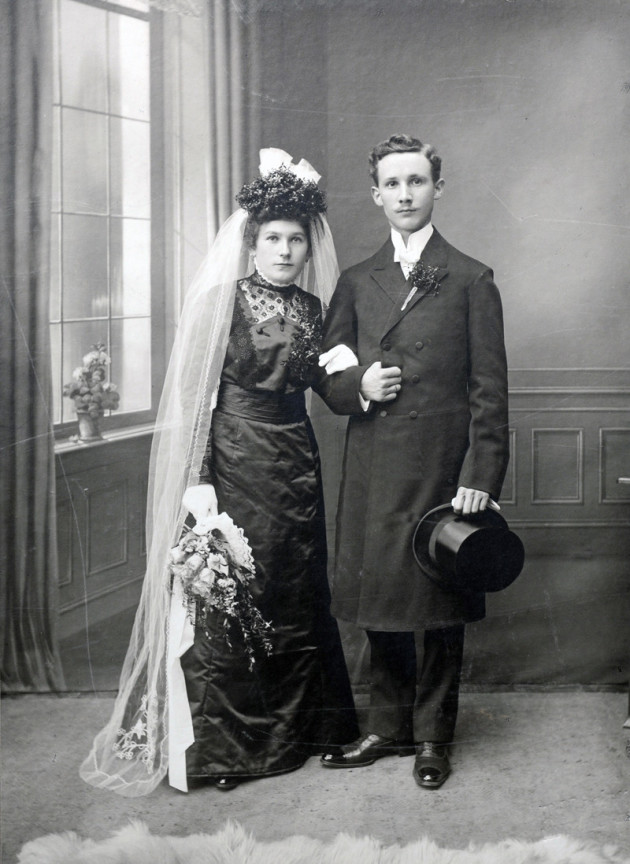 Zum Thema Ahnenforschung sieht man ein altes Foto mit einem Brautpaar, sie links er rechts, er hält einen Zylinder in der Hand. beide schauen zur Kamera.
